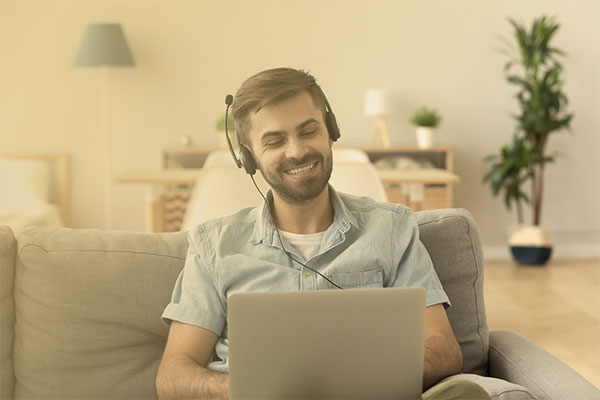 man wearing a headset and working via a laptop