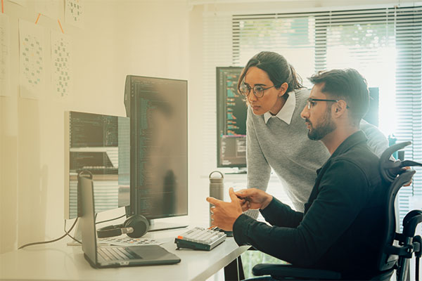 A man and woman working on a computer.