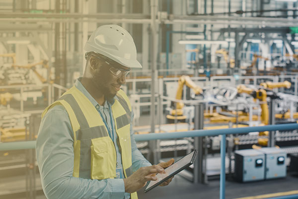 Engineer in high visibility vest using tablet computer to look at data