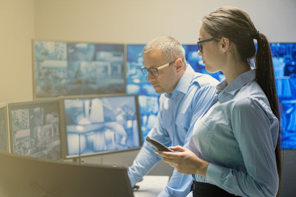 Woman and man monitoring multiple computer screens