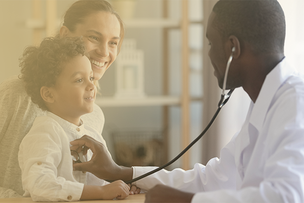 Image of a parent holding their child while a male nurse uses a stethoscope