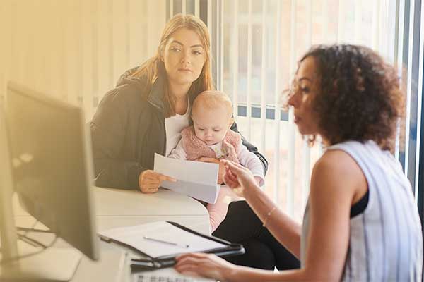 Image of woman with baby speaking with professional woman