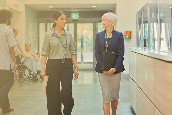 Two women walking and talking down the hallway of a medical facility